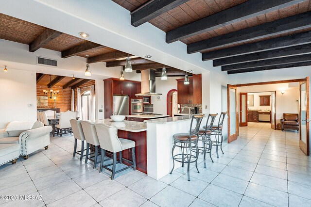 kitchen featuring exhaust hood, a peninsula, visible vents, wooden ceiling, and stainless steel appliances