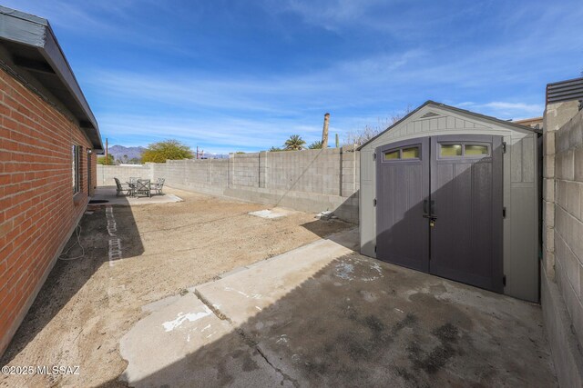 view of patio with a fenced backyard, an outbuilding, and a storage shed