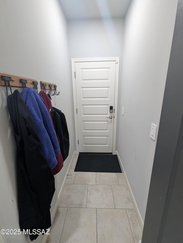 doorway with light tile patterned floors and baseboards