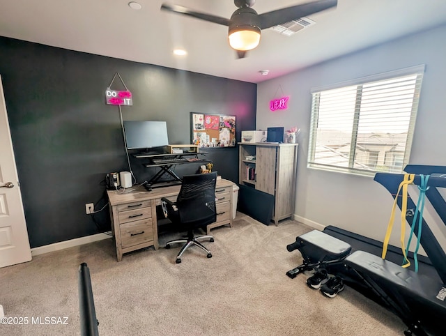 office space featuring baseboards, visible vents, light colored carpet, and a ceiling fan