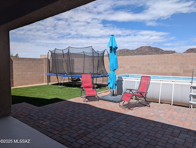 view of patio with a fenced backyard, a trampoline, and a fenced in pool