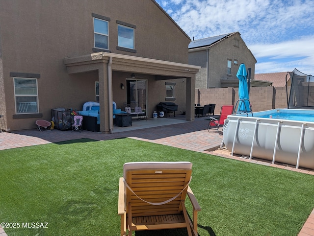 rear view of house with a fenced in pool, stucco siding, fence, and a lawn