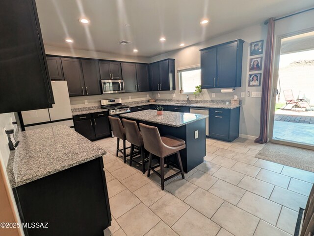 kitchen featuring light stone countertops, a kitchen breakfast bar, recessed lighting, a center island, and stainless steel appliances