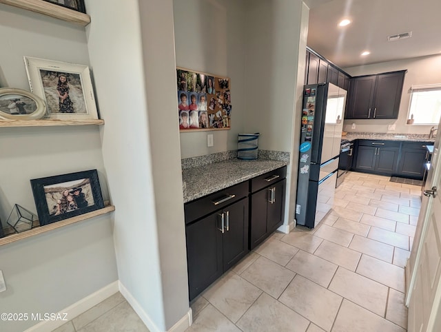 kitchen featuring light stone counters, recessed lighting, light tile patterned floors, freestanding refrigerator, and visible vents