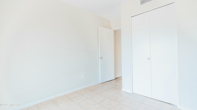 unfurnished bedroom with baseboards, visible vents, a closet, and light tile patterned floors