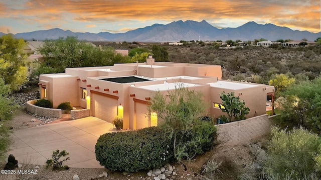 exterior space featuring a chimney, fence, concrete driveway, stucco siding, and a mountain view