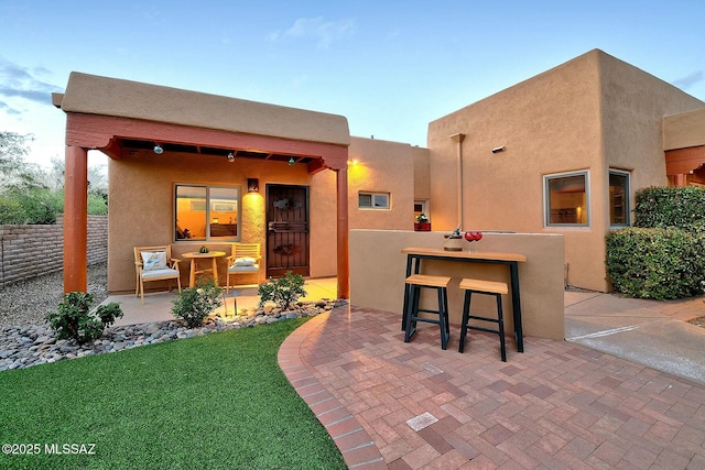 rear view of property featuring stucco siding, outdoor dry bar, and a patio