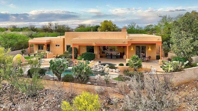 rear view of house featuring a patio area, fence, a fenced in pool, an outdoor hangout area, and stucco siding