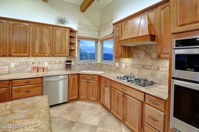 kitchen featuring a sink, custom exhaust hood, backsplash, light stone counters, and appliances with stainless steel finishes