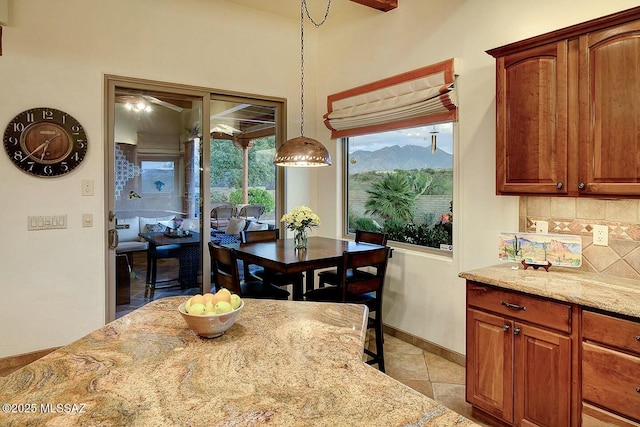 dining area featuring baseboards, a ceiling fan, a mountain view, and light tile patterned floors