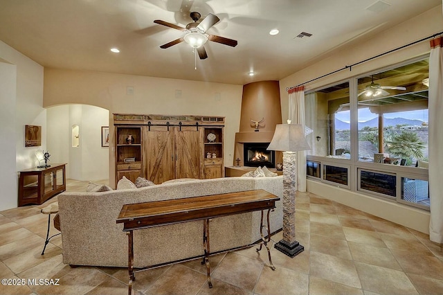 living room with recessed lighting, visible vents, a ceiling fan, arched walkways, and a large fireplace
