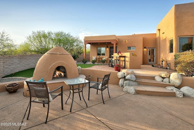 view of patio / terrace featuring a lit fireplace and fence