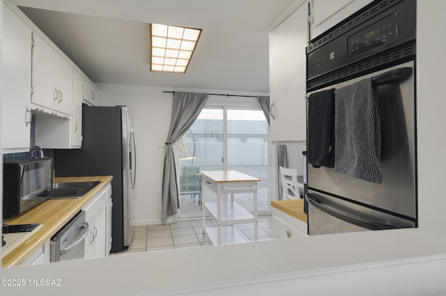 kitchen with white cabinets, light countertops, baseboards, appliances with stainless steel finishes, and light tile patterned floors