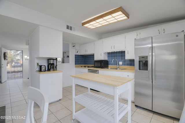 kitchen featuring light countertops, visible vents, stainless steel appliances, a sink, and backsplash