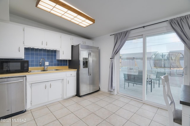 kitchen with light countertops, backsplash, a sink, stainless steel appliances, and white cabinets