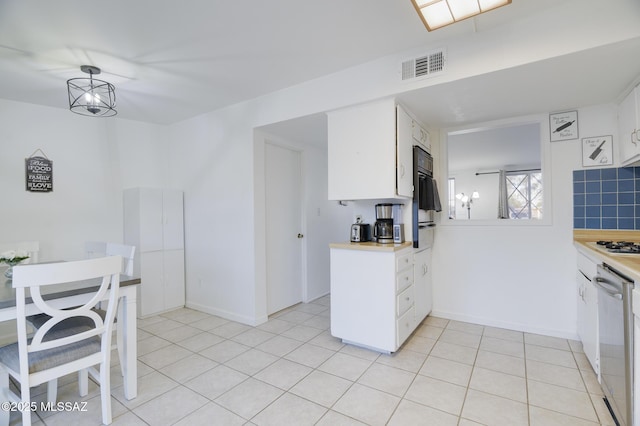 kitchen with light tile patterned flooring, light countertops, visible vents, dishwasher, and white cabinetry