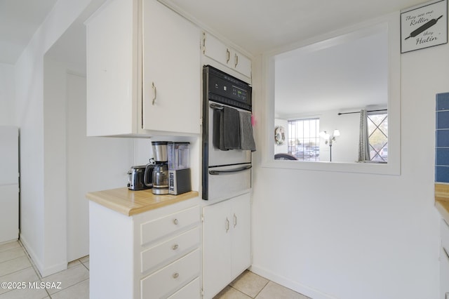 kitchen with light tile patterned flooring, light countertops, white cabinets, wall oven, and a warming drawer