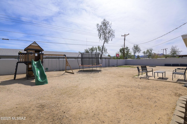 view of playground with a trampoline and fence