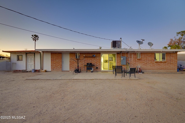 back of property with brick siding, central air condition unit, and a patio