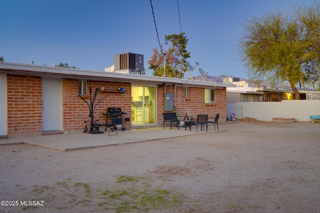 rear view of property featuring fence, cooling unit, a patio, and brick siding