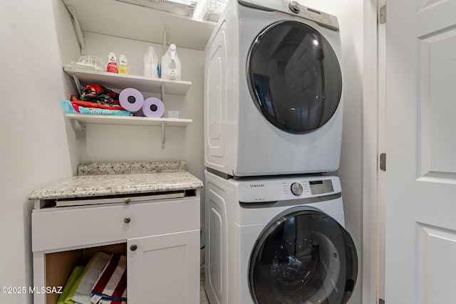 laundry area featuring cabinet space and stacked washing maching and dryer