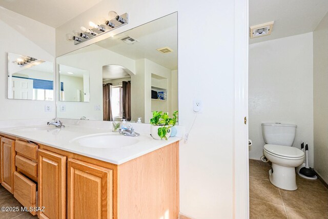 bathroom featuring toilet, a sink, double vanity, and visible vents