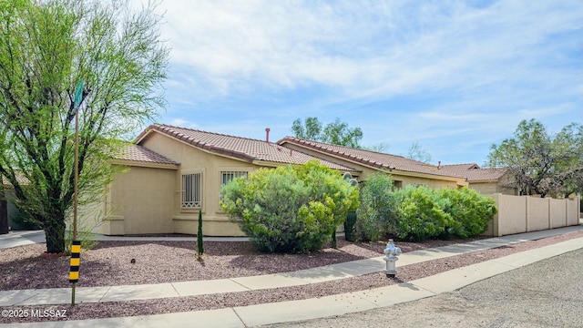 view of front of property with stucco siding, fence, and a tiled roof