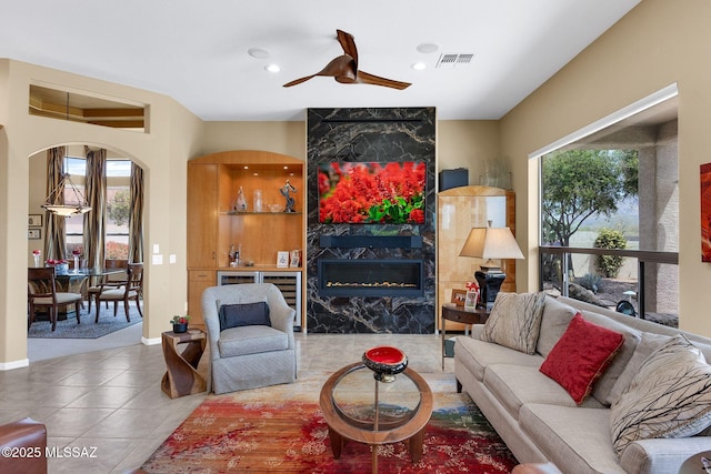 39425 S Mchaney Ct, Tucson, AZ 85739 - living area with tile patterned floors, a high end fireplace, visible vents, arched walkways, and ceiling fan