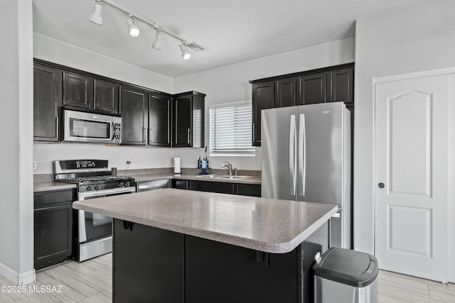 kitchen featuring a breakfast bar, stainless steel appliances, a kitchen island, a sink, and dark cabinetry