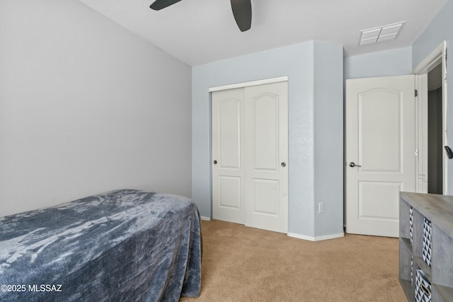 bedroom with a closet, a ceiling fan, light carpet, baseboards, and visible vents