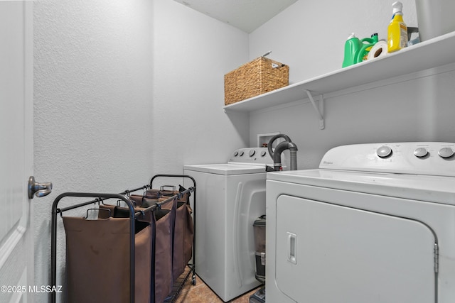 clothes washing area featuring a textured wall, independent washer and dryer, and laundry area