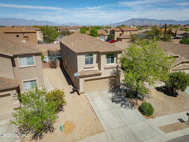 view of front of home featuring a residential view, stucco siding, an attached garage, and a mountain view