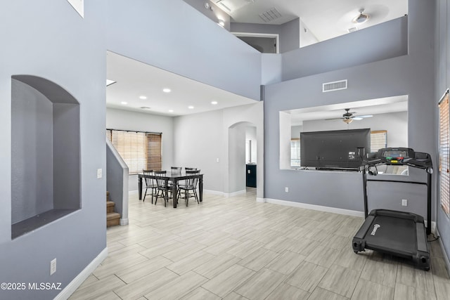 workout room featuring a ceiling fan, arched walkways, baseboards, and visible vents