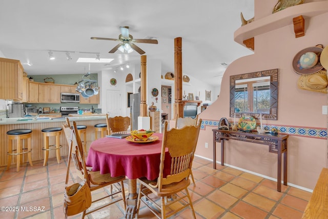 dining space with track lighting, ceiling fan, lofted ceiling, and light tile patterned floors