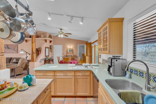 kitchen featuring light brown cabinets, vaulted ceiling, a sink, light countertops, and a peninsula