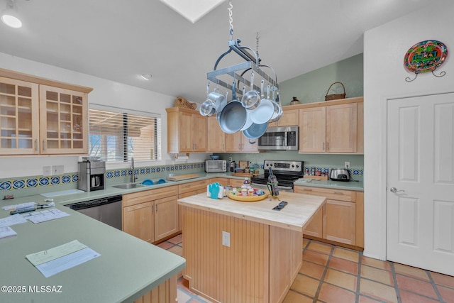 kitchen with light brown cabinetry, a sink, lofted ceiling, butcher block counters, and appliances with stainless steel finishes
