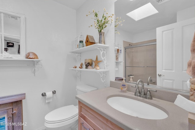 bathroom featuring vanity, a skylight, a stall shower, and toilet