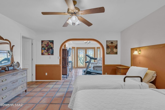 bedroom featuring arched walkways, a ceiling fan, and light tile patterned flooring