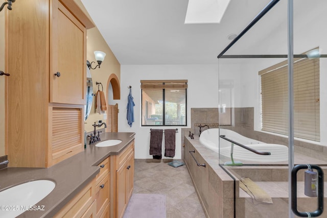 bathroom with double vanity, tile patterned floors, tiled tub, and a sink