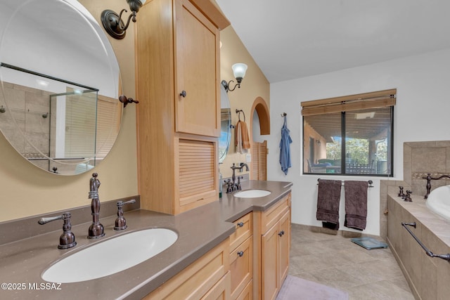 full bathroom with a bath, double vanity, and a sink