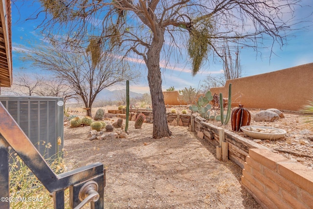 view of yard featuring central air condition unit, fence, and a mountain view