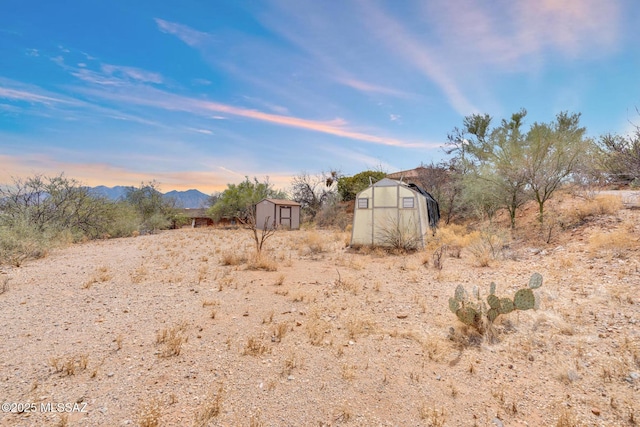 view of yard with an outdoor structure, a storage unit, a greenhouse, and a mountain view