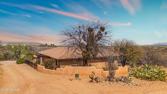 view of property exterior featuring stucco siding, a tiled roof, fence, and a mountain view