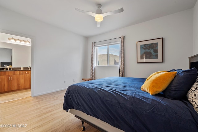 bedroom with connected bathroom, a sink, a ceiling fan, baseboards, and light wood-style floors