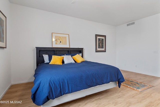 bedroom featuring baseboards, visible vents, and wood finished floors
