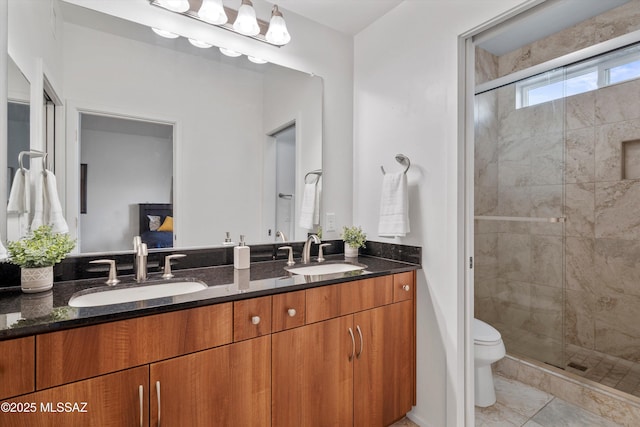 bathroom with toilet, a sink, a stall shower, and double vanity