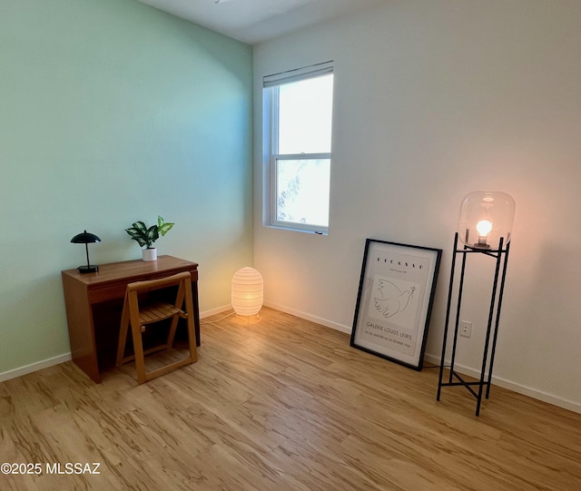 living area featuring baseboards and light wood finished floors
