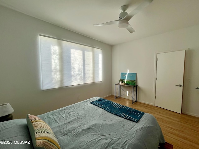 bedroom with baseboards, ceiling fan, and wood finished floors