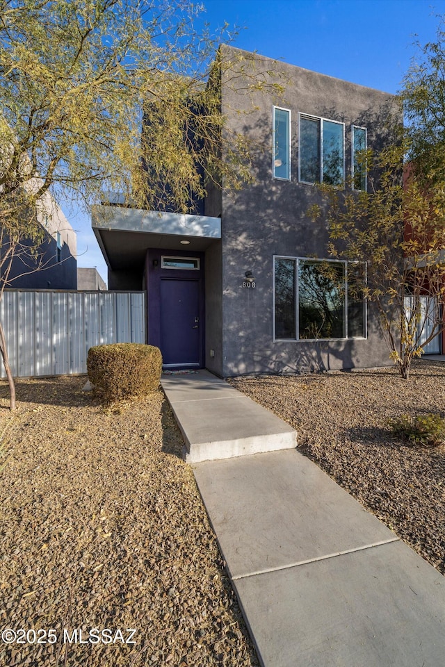 view of front of home with stucco siding and fence