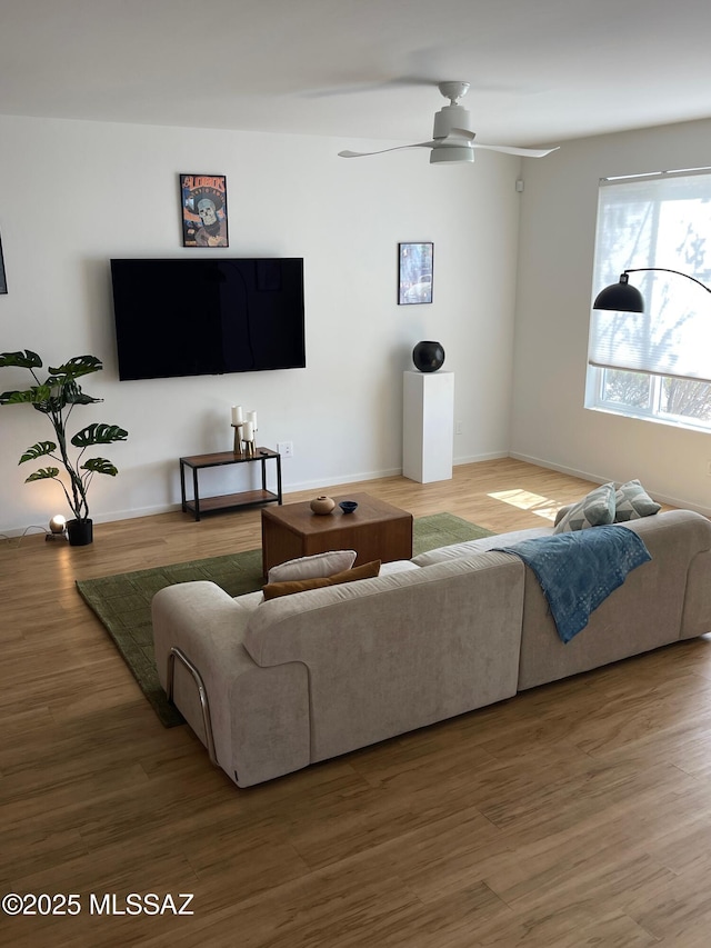 living room with a ceiling fan, baseboards, and wood finished floors